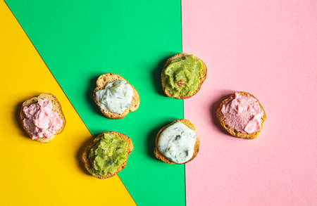 Appetizing crostini or bruschetta with tarama, tzatziki and guacamole sauce. Variety of small sandwiches with various toppings on the multicolored backgroundの写真素材