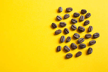 Coffee beans close-up on a bright yellow background with copy spaceの写真素材