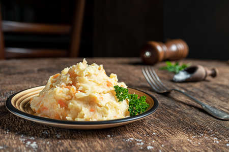 Mashed parsnips with potatoes and carrots on a dark wooden background close-up. Delicious and healthy vegetarian food rich in vitamins and minerals.の写真素材