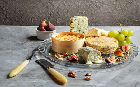 Assortment of French cheese - camembert, roquefort, brie, goat cheese and epoisse with grapes, figs...