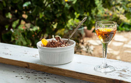 Belgian traditional tangerine liqueur and chocolate mousse, garnished with a tangerine wedge and white chocolate shavings on a windowsill against the backdrop of a summer gardenの写真素材