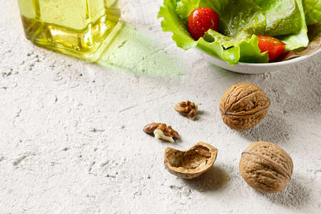 Walnuts, a bottle of walnut oil, walnuts and salad on a gray background, olive oil alternative with...