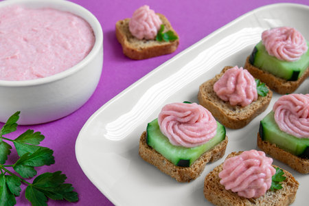 A white plate with taramasalata crostini and a white bowl with tarama on the purple background close-upの写真素材