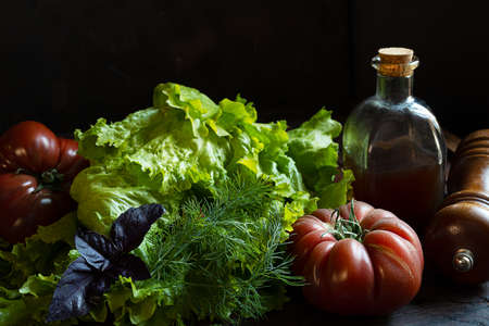 Organic tomatoes, fresh salad and a bottle with pumkins oil on an old wooden table, the concept of gardening and growing your own foodの写真素材