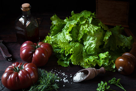 Fresh organic salad, tomatoes, a bottle with pumpkin seed oil on an old wooden table, the concept of healthy eating and vegetarianism, low key styleの写真素材
