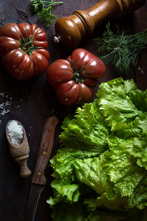Organic fresh tomatoes and salad from a vegetable garden on an old wooden table, the concept of dieting and healthy food, rustic style, top viewの写真素材