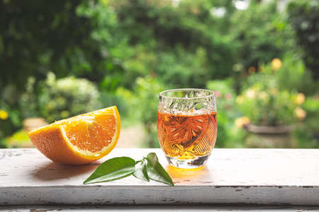 A shot of traditional Belgian tangerine liqueur on a windowsill against the backdrop of a summer gardenの写真素材