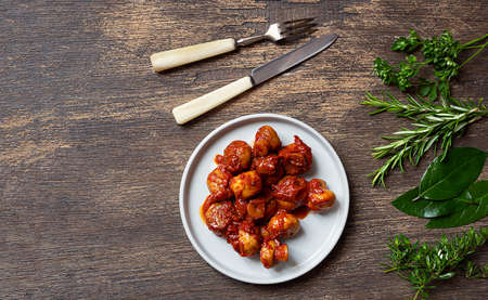 Greek style mushrooms, cutlery and herbs - bay leaves, parsley, rosemary, thyme on a dark wooden background, top view with copy spaceの写真素材