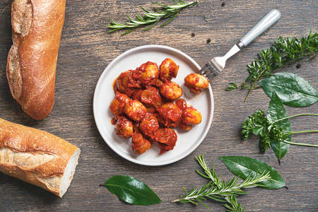 Greek style mushrooms, bread and herbs - bay leaves, parsley, rosemary, thyme on a dark wooden background, top viewの写真素材