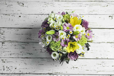 Bouquet of white, pink and yellow garden flowers on a white wooden table, top viewの写真素材