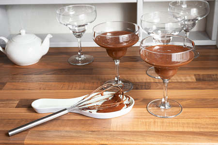 Bowls with chocolate mousse and whisk on the countertop of a Scandinavian-style kitchenの写真素材