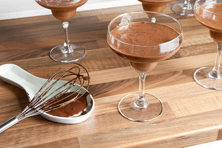 Chocolate mousse in a bowls and whisk on a wooden table close-upの写真素材