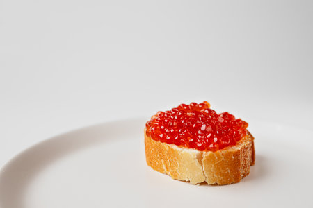A red caviar sandwich on a plate on a white tableの写真素材