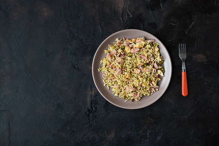 Plate of Cantonese rice or Chinese fried rice and fork on dark table, top view with copy spaceの写真素材