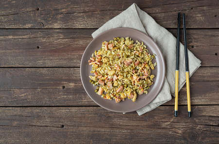 Traditional Cantonese rice or Chinese fried rice in a plate on a dark wooden old table, top view with copy spaceの写真素材