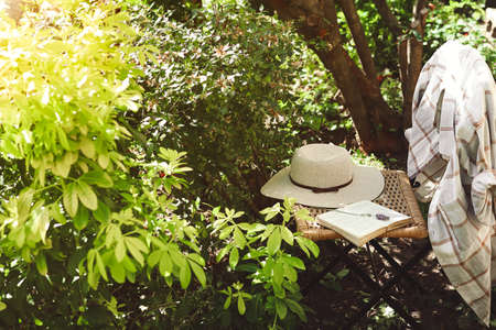 An open book and women's summer hat on old wicker chair in garden, provence and nature slow life conceptの写真素材