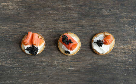 Three blini pancakes with black sturgeon caviar and salmon on a wooden tableの写真素材
