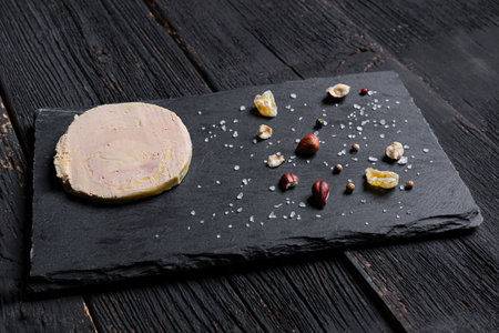 Traditional French foie gras on a slate with peppercorns, hazelnuts, salt and dried fruitsの写真素材