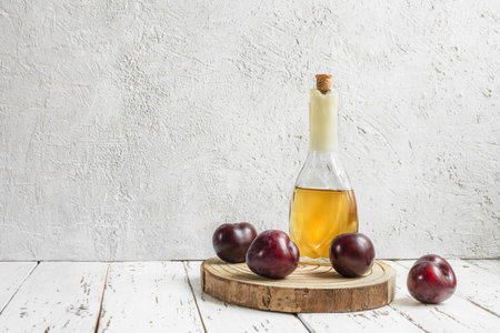 Rakija or rakia slivovica - traditional Balkan plum brandy in the bottle and fresh plums on the light backgroundの写真素材