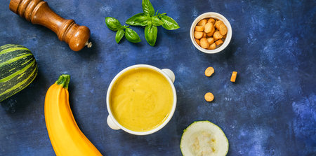 Zucchini vegetarian soup in a white bowl on a blue background, top view with copy spaceの写真素材
