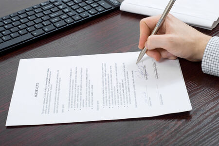 Business person signing contract at his desk
