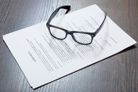 Glasses on the table with contract papersの写真素材