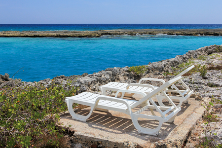 two chaise-lounges on the coral beach of the Caribbean seaの写真素材