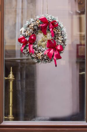 Christmas decoration as holiday fir wreath, bow and cones on the glass doorの写真素材