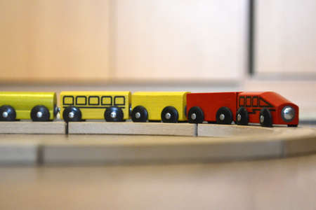 The red-yellow wooden train rides on the toy railway. Toy for preschoolers, developing game