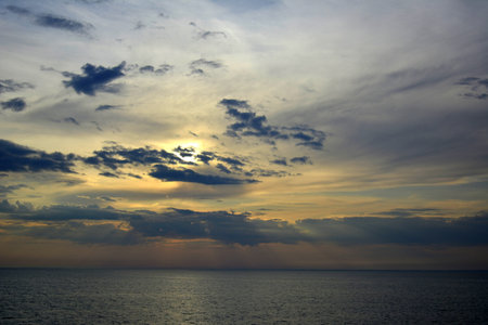 Baltic sea. July, 24, 2014. Sunset over calm sea, sun hidden in clouds. Soft view of the sun behind...