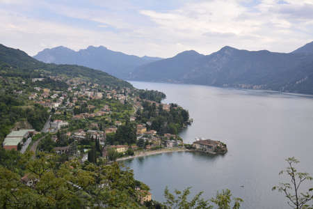 Panorama of mountain lake Como surrounded by green hills covered with cedar forestの写真素材