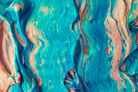 Rough strokes of paint. Artistic fluide abstract volume texture with blue color and orange tint. Thick heavy layer of flowing colored acrylic foam paintの写真素材
