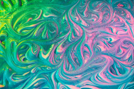 Liquid marble background. Vibrant fluid art texture. Light trendy modern background at vibrant green and pink colors. Volume relief with colorful aqrylic ink foam and glitterの写真素材