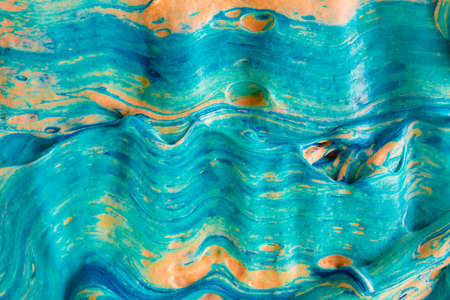 Fluid art marble abstract volume texture with blue color and orange tint. Horizontal bold rough strokes of liquid paint. Artistic Thick heavy bold smears of flowing oil acrylic paint.の写真素材