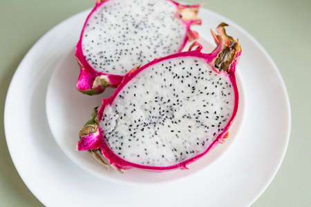 Pitahaya Dragon Fruit with fresh pulp, half cutted on a white plateの写真素材