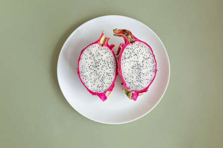 Pitahaya Dragon Fruit fresh half cutted, served on a white plate. Pitaya with white pulp and balck seeds on pale green background.の写真素材