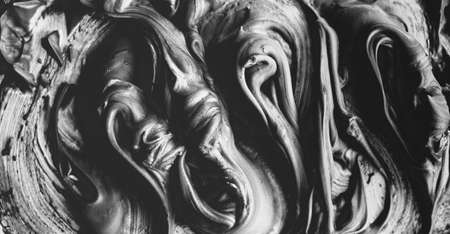 Mixed black and gray acrylic foam background. Liquid smooth relief texture. Thick bold fluid acrylic foam texture is mixed. Heavy thick paint strokes. Monochrome texture with muted shadowsの写真素材