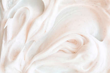Creamy texture of white airy scrub foam with peeling particle. Gentle cosmetic background with warm light bege hue.の写真素材