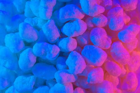 Corn sticks in sugar powder. Sweet food background. Corn sticks in mixed colorful blue and pink light. Crispy, sweet and fun snack for party and movie timeの写真素材