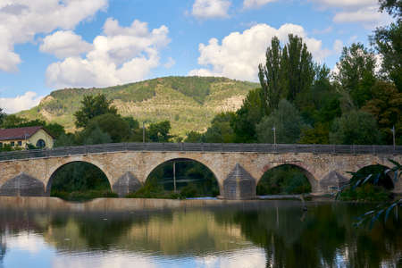 Beautiful old bridge over a calm river on a Sunny dayの写真素材