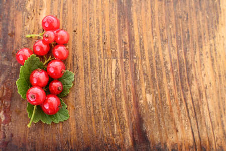 Red currant with leaves on old wooden plankの写真素材