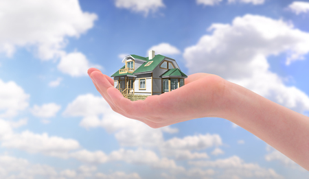 House in hand over blue sky. Mortgage concept.の写真素材