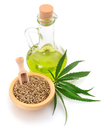 Hemp oil in glass bottle and fresh green hemp leaves on white background.の写真素材