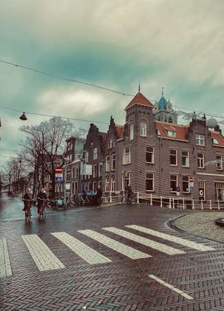 Delft, Netherlands - January 27,, 2021: Colorful street panoramic view with traditional dutch houses on the square, bicycles, people walking in downtown of popular Holland destinationのeditorial素材