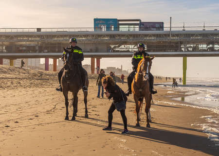 Scheveningen, The Hague, The Netherlands, 22 January 2021: two policemen riding a horse on a beach in Scheveningen, The Hague, The Netherlandsのeditorial素材