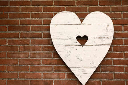 wooden white heart on a brick red wall background, love symbol. copy spaceの写真素材