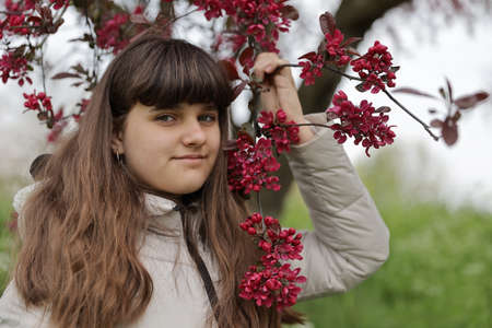 close up smiling caucasian portrait of girl, young woman outdoor, red blossom tree background in the Netherlandsの写真素材