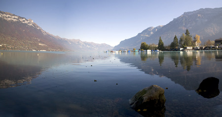 Horizontal view of lake between mountains with village in switzerlandの写真素材