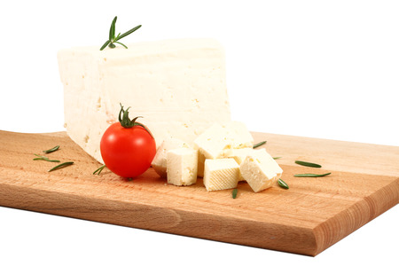 Piece of white cheese placed on a wooden board. Isolated white background.の写真素材