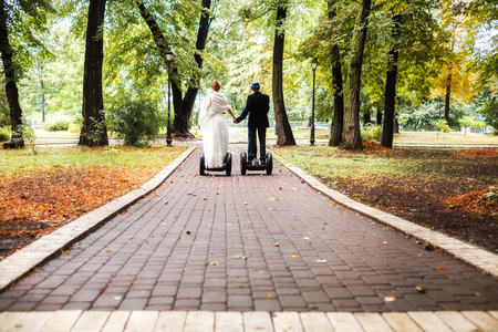 Bride and Groom on segways together in the autumn parkの写真素材